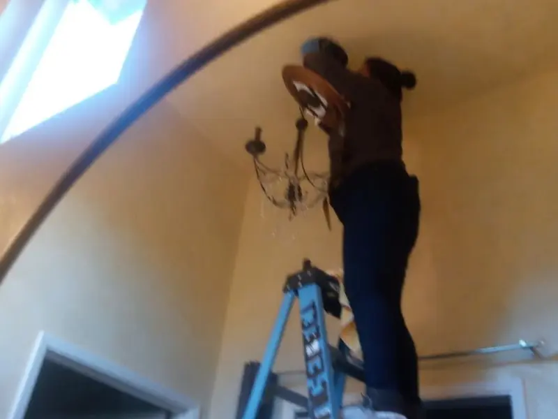 Electrician installing a chandelier in a Bowie residence